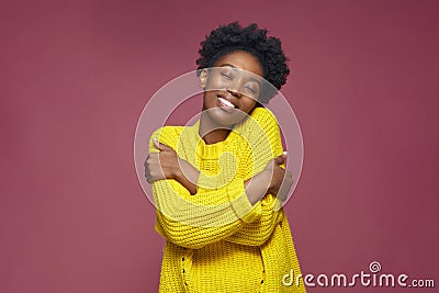 Love yourself, self acceptance. Smiling young african american woman embrace herself, closed eyes. Self-care concept Stock Photo