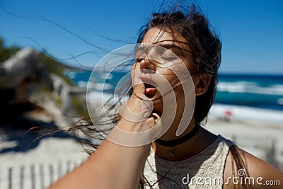 A loved one touches his girlfriend`s lips, passion, love affair on the beach of the Corsica island, seascape background. Stock Photo