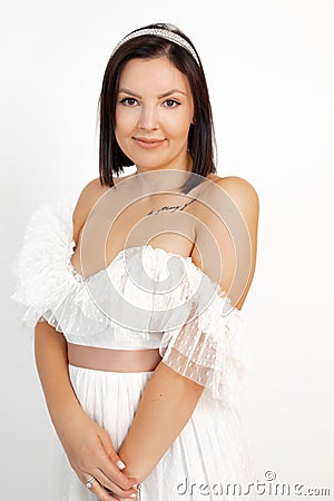 Lovely adult brunette woman in romantic white dress with tattoo on chest isolated on white background, copy space Stock Photo