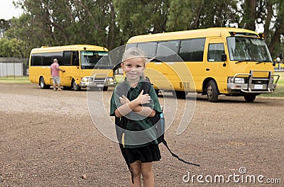 Beautiful blond Caucasian female child waiting for school bus carrying backpack smiling happy in student young girl and schoolgirl Stock Photo