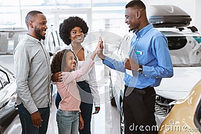Lovely black girl high fiving friendly salesman at auto dealership Stock Photo