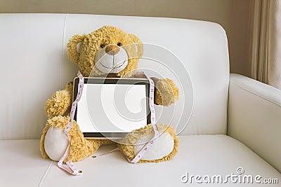 Lovely brown bear gift doll an taplet and tape measure on sofr Stock Photo