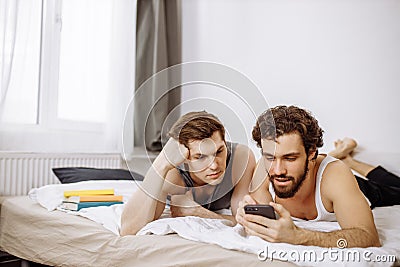 Lovely caucasian gays on bed, use mobile phone Stock Photo