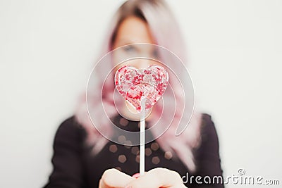 Lovely charming girl with a Lollipop in the form of heart. Portrait of a young woman with pink hair and pink candy Stock Photo