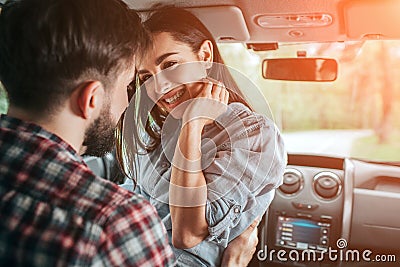 Lovely couple is sitting alone in car. Girl is sitting face to face with her boyfriend. She is keeping her hand close to Stock Photo