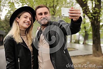 Lovely couple with smartphone taking selfie on spring day Stock Photo