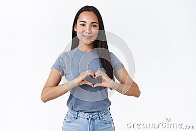 Lovely, friendly-looking tender asian girl confess in love, show heart sign and smiling silly as happy have such great Stock Photo