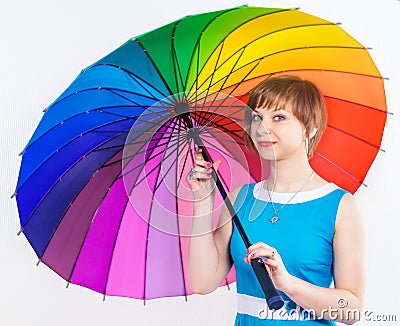 Lovely girl in blue dress under colorful positive rainbow Umbrella on white background. Studio shot, copy space Stock Photo