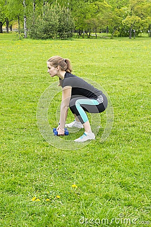 Lovely girl goes in for sports outdoors using dumbbells Stock Photo