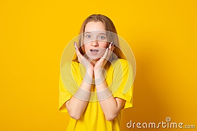 Lovely girl has fun as attends funny show, smiles broadly, keeps hands on cheeks, being amused and entertained. Stock Photo