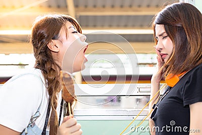 Lovely girl is using hand close her nose because her friend persecute and blow her bad breath to her. She eat some stink food. Pr Stock Photo