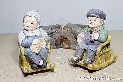 Lovely grandparent doll siting rocking bamboo chair on wood background. -still life. Stock Photo