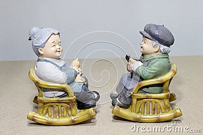 Lovely grandparent doll siting rocking bamboo chair on wood background. -still life. Stock Photo