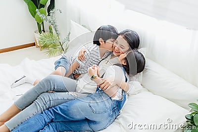 Lovely happy Asian family at cozy home. Son and daughter kiss mother with enjoy ,relax and playful together in bedroom. Happiness Stock Photo