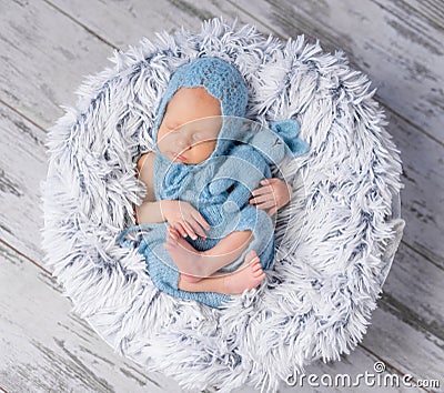 Lovely infant in hat and jumpsuit sleeping on round bed Stock Photo