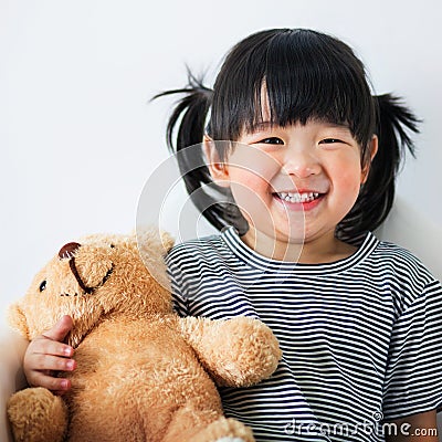 Lovely and innocent asian kid with teddy smiled happily Stock Photo