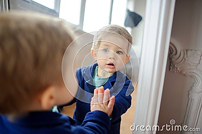 The lovely kid looks in a mirror. Stock Photo