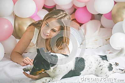 Lovely lady in pajama in bedroom play with her dog. Indoor portrait girl with baloons in morning. Husband surprising his wife Stock Photo