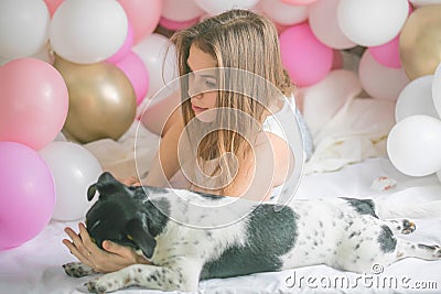 Lovely lady in pajama in bedroom play with her dog. Indoor portrait girl with baloons in morning. Husband surprising his wife Stock Photo