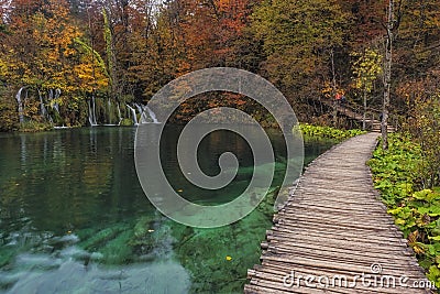 Lovely landscape with beautiful waterfall, wooden path and autumn forest Stock Photo