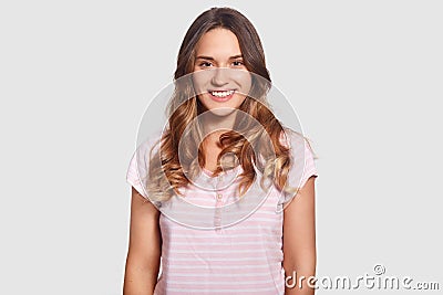 Lovely merry beautiful young Caucasian female in casual pyjamas, being in good mood ater good sleep, isolated over white backgroun Stock Photo