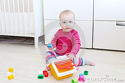 Lovely 10 months baby girl plays house shape sorter Stock Photo