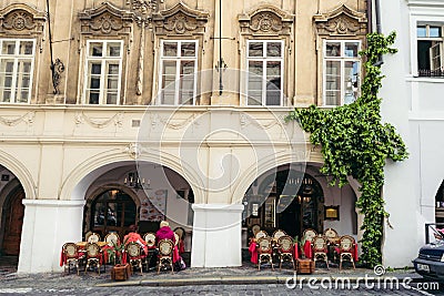 Lovely old street cafe full of people. The building is overgrown with plants. Prague location. Editorial Stock Photo