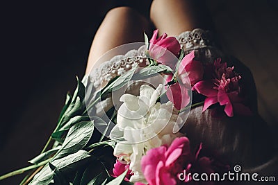 Lovely pink peonies on legs of boho girl in white bohemian dress Stock Photo