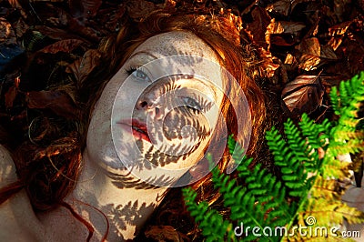 Lovely portrait of a young seductive foxy girl in autumn, with shadow of fern frond on face, beautiful sexy attractive redhead Stock Photo