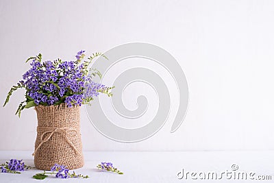 Lovely purple flower in sack vase on white wooden table Stock Photo