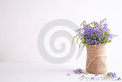 Lovely purple flower in sack vase on white wooden table Stock Photo