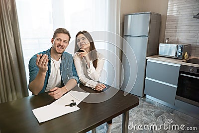 Lovely satisfied couple man and woman sitting in their new cosy apartment after successful lease sign Stock Photo