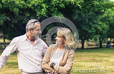 Lovely senior elderly smiling couple man and woman look at each other in romantic moment in the park. Warm heart marriage and love Stock Photo