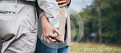 Lovely senior elderly smiling couple man and woman holding hand as promising of forever love or take care in romantic moment. Warm Stock Photo