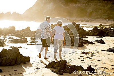 Lovely senior mature couple on their 60s or 70s retired walking happy and relaxed on beach sea shore in romantic aging together Stock Photo