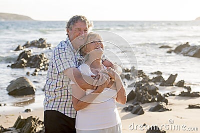 Lovely senior mature couple on their 60s or 70s retired walking happy and relaxed on beach sea shore in romantic aging together Stock Photo