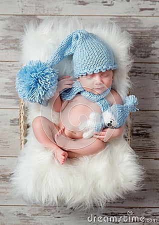 Lovely sleeping baby in hat with big pompon on fluffy cot Stock Photo