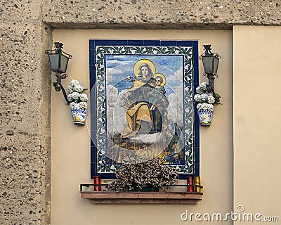 Lovely small altar with a painting of Madonna on mosaic tiles in a wall niche in Seville, Andalusia, Spain. Editorial Stock Photo