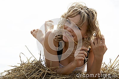 Lovely smiling woman lying on haystack outdoors Stock Photo