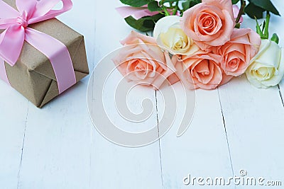 Lovely soft orange pink color rose tied by pink ribbon and brown gift box on white wood table background, sweet valentine present Stock Photo