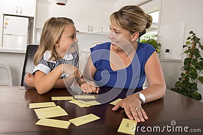 Lovely sweet and happy 6 years old daughter learning reading with flash card words game at home kitchen playing with her young bea Stock Photo