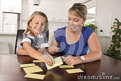 Lovely sweet and happy 6 years old daughter learning reading with flash card words game at home kitchen playing with her young bea Stock Photo