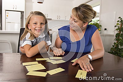 Lovely sweet and happy 6 years old daughter learning reading with flash card words game at home kitchen playing with her young bea Stock Photo