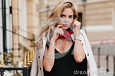 Lovely tanned female model wears golden jewelry posing before date. Outdoor portrait of good-looking blonde woman with Stock Photo