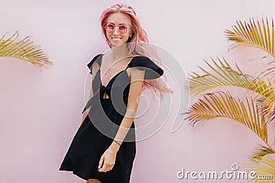 Lovely tanned girl in black dress posing in studio and laughing. Indoor portrait of carefree caucas Stock Photo