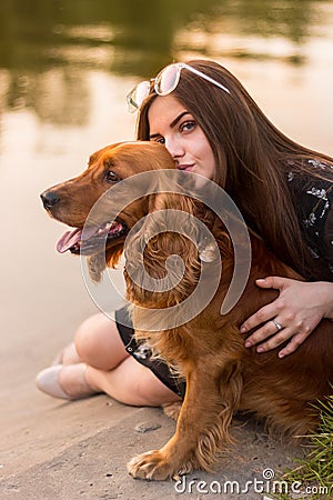 Lovely tanned woman in elegant glasses fooling around with dog Stock Photo