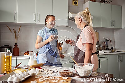 Friendly girl and her caring grandma drinking tea at home Stock Photo