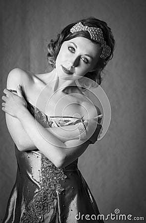 Lovely twenties woman wearing diamond hair accessory and bracelet, posing in a vintage grey evening dress Stock Photo