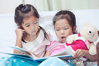 Lovely twin sister two child girls having fun to read a cartoon Stock Photo