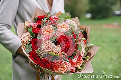 Lovely woman holding a beautiful autumn bouquet. flower arrangement with carnations and red garden roses. Color pink Stock Photo